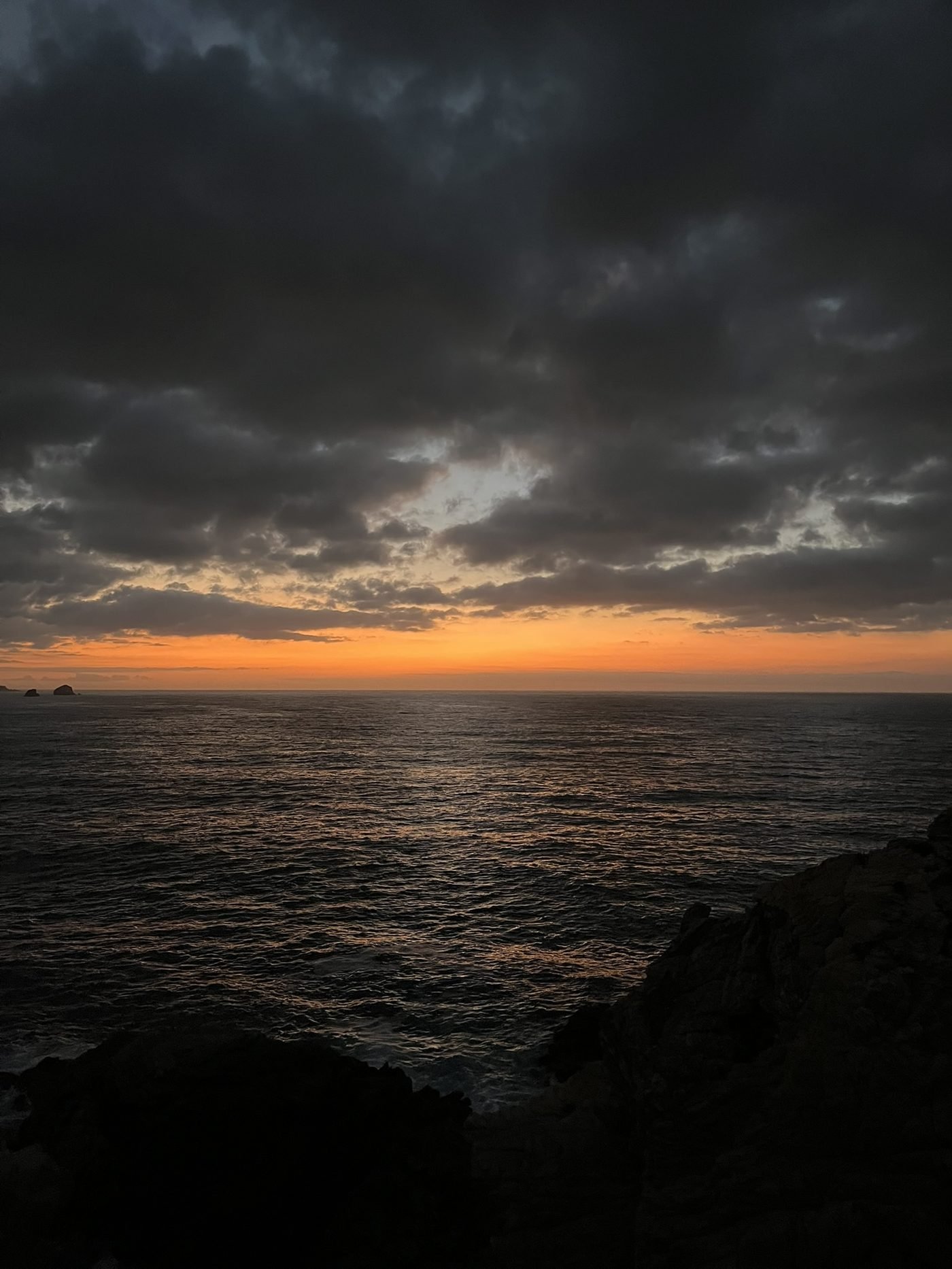 Atardecer sobre el Pacífico desde los acantilados de Punta Cometa, con nubes y mar en calma