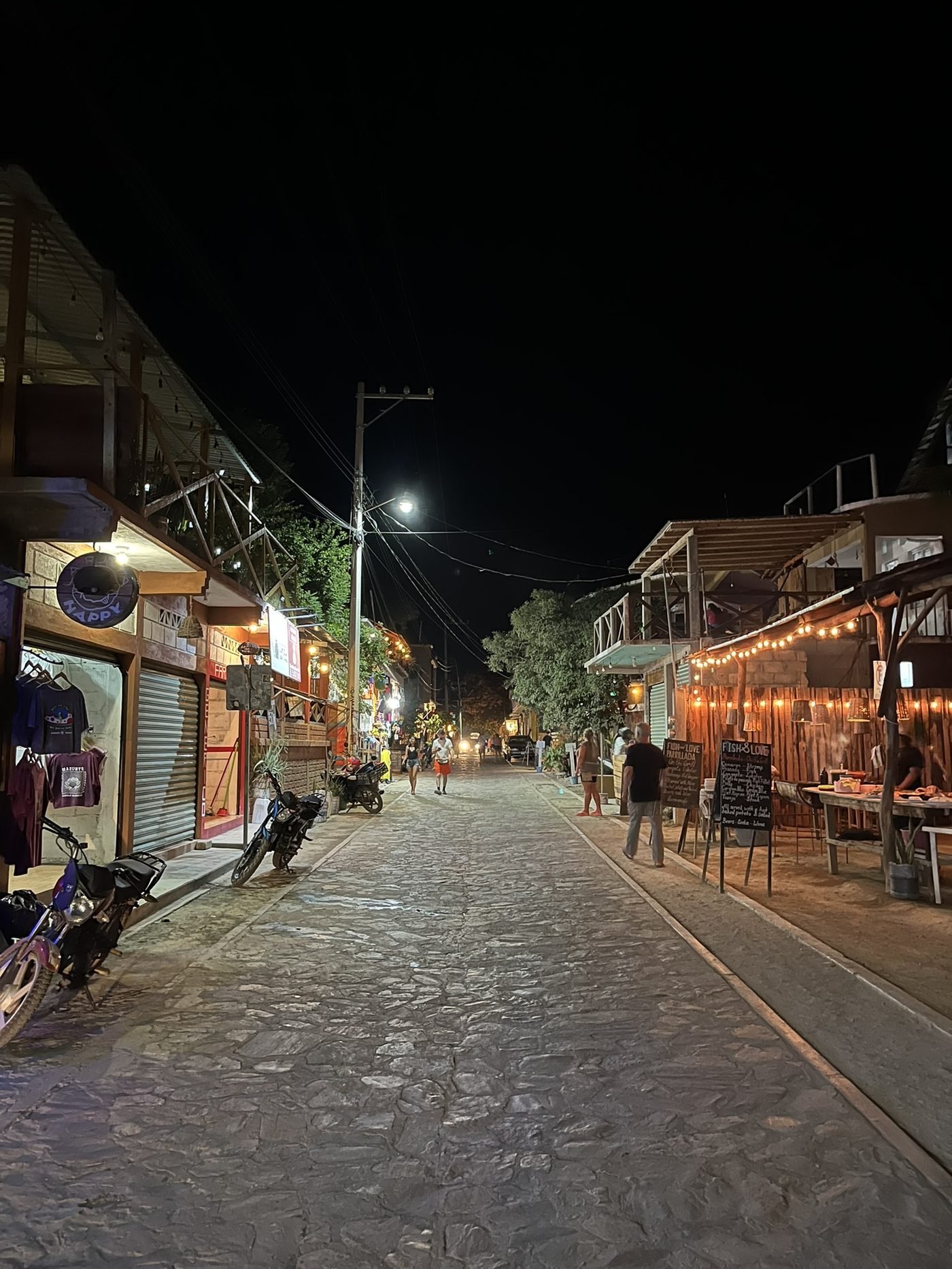 Calle principal de Mazunte de noche, con comercios iluminados y vida local