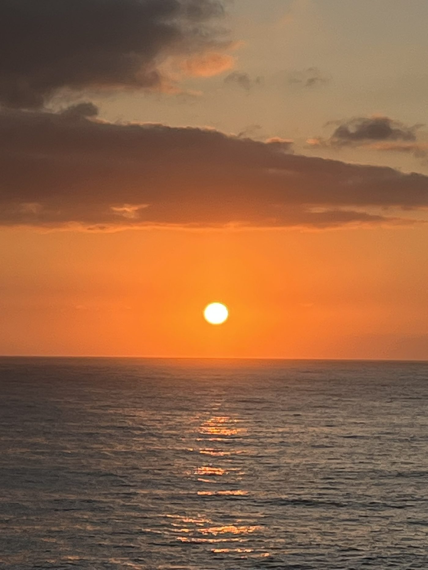El sol como una esfera dorada sobre el mar, con su reflejo extendido en el agua como una cauda de cometa